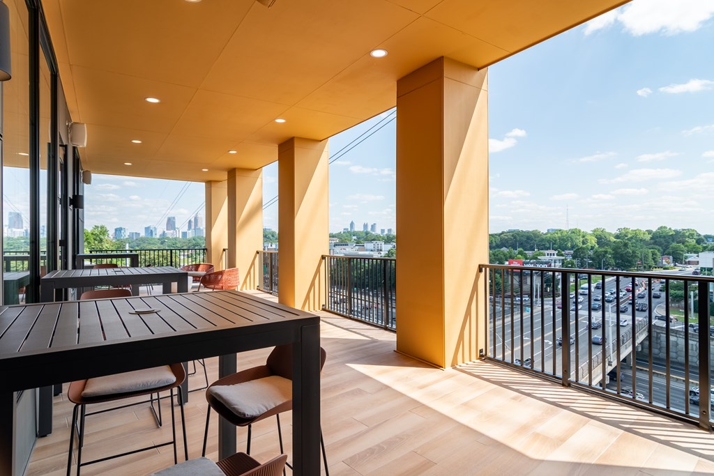 A balcony with a table and chairs overlooking a city street.