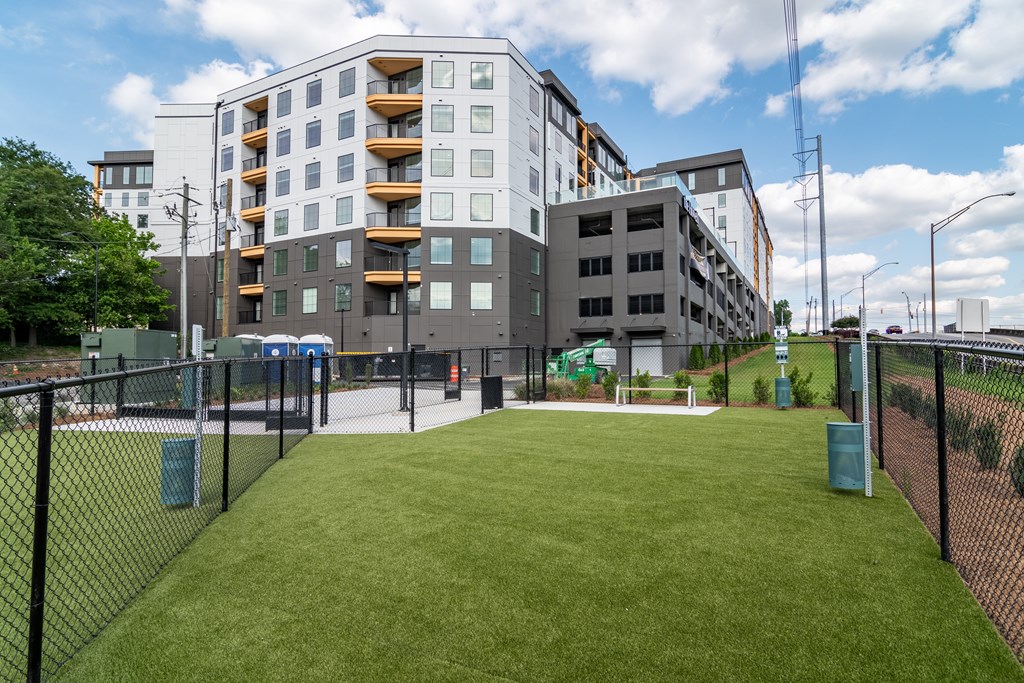 A grassy area in front of a building with a fence on the left side.