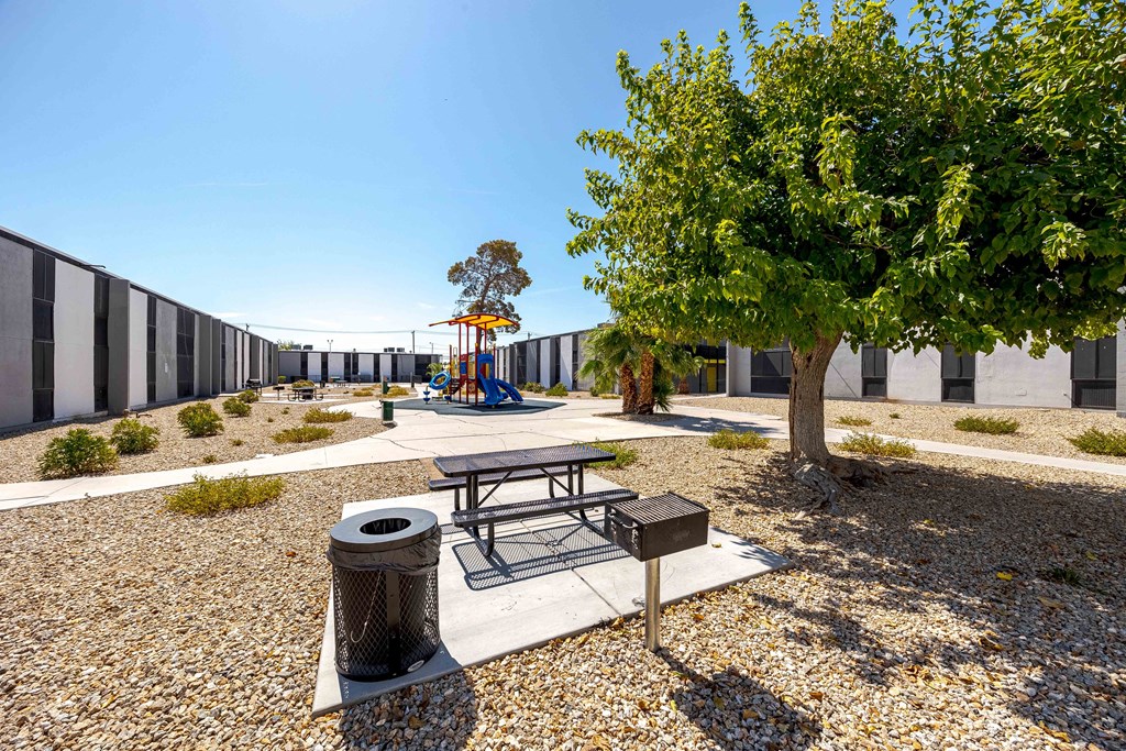 a playground with a picnic table and a tree in front of a building