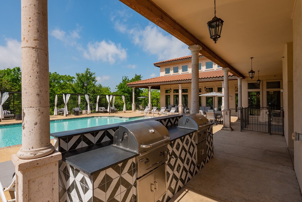 a covered patio with a swimming pool and a clubhouse in the background