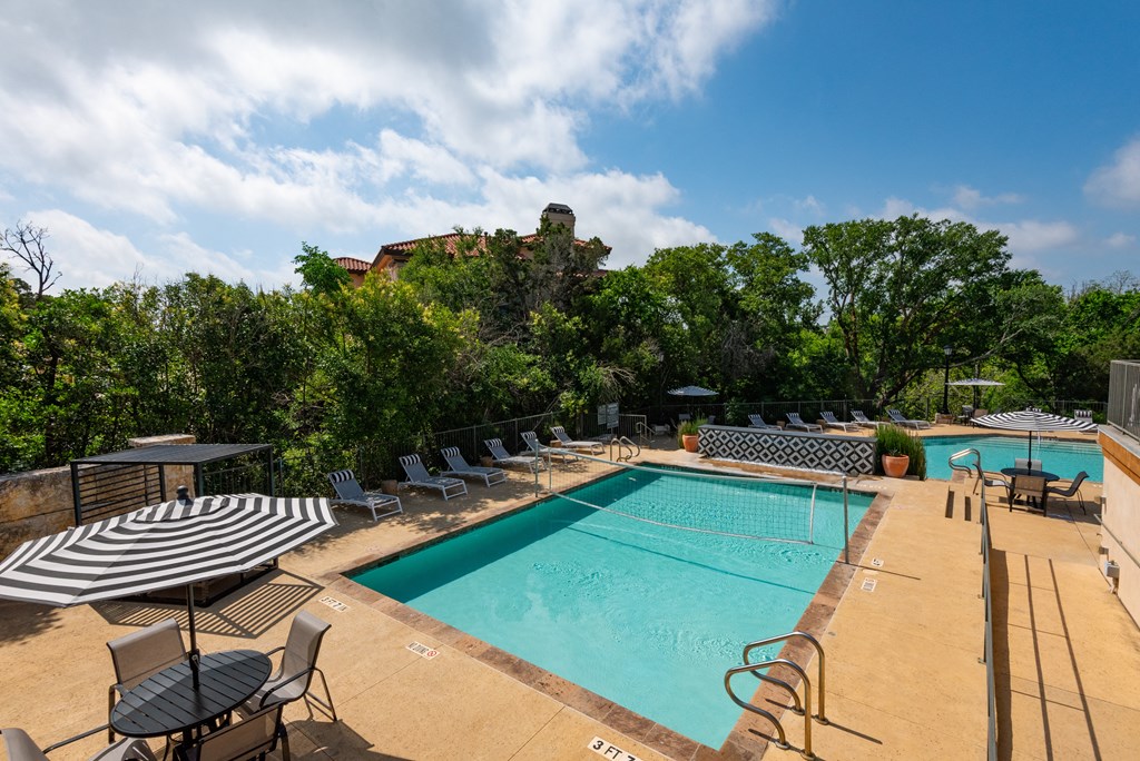 a resort style pool with lounge chairs and umbrellas