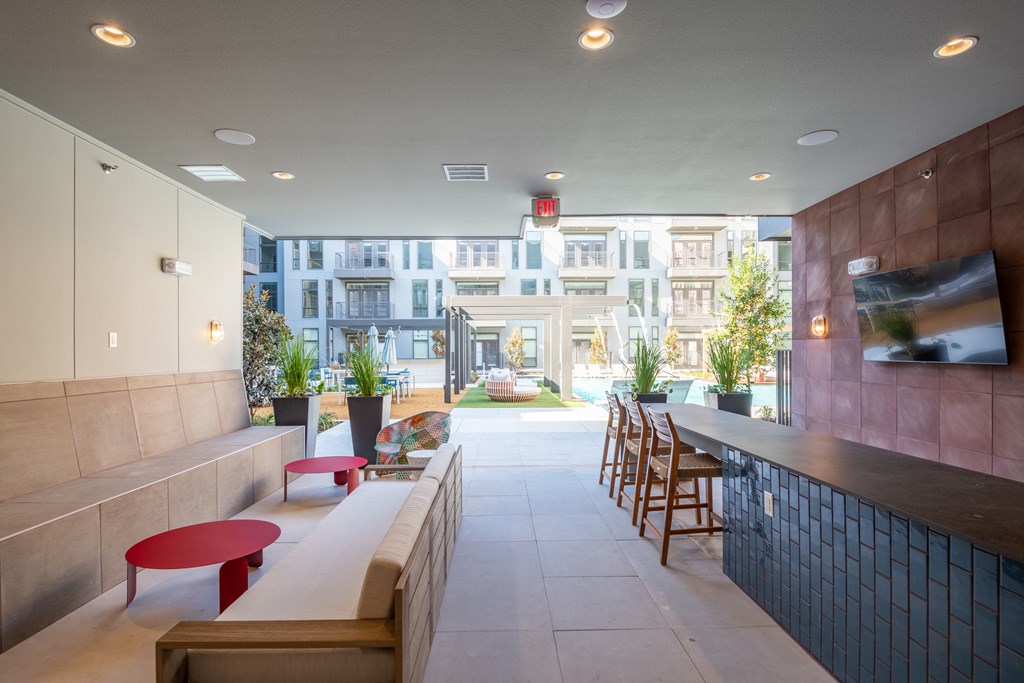 a seating area with a long counter and chairs in front of a building