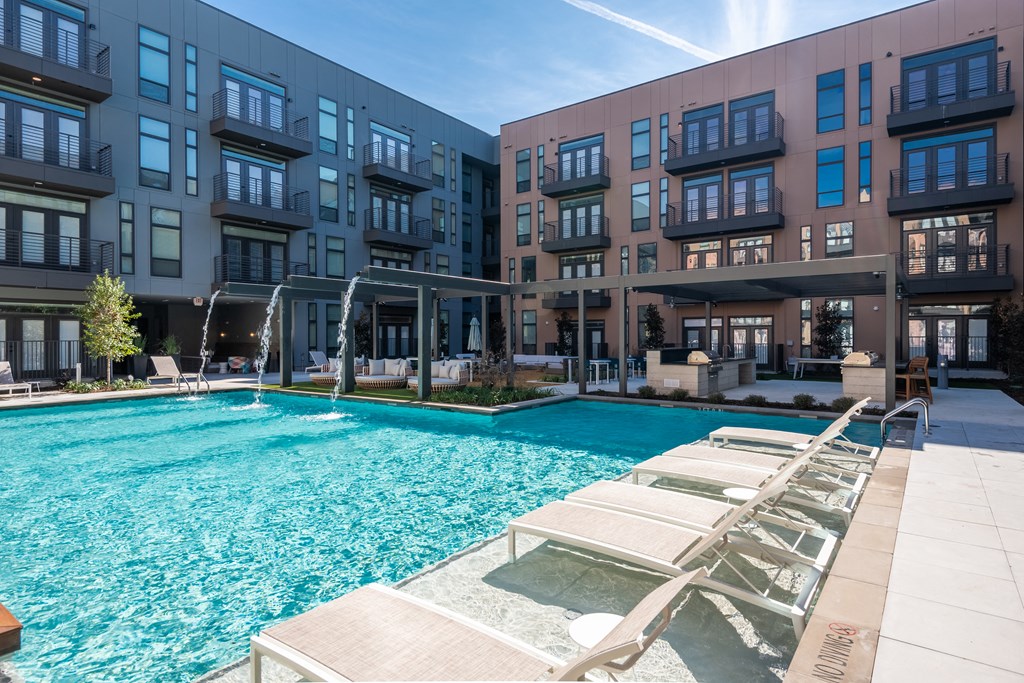a swimming pool with lounge chairs in front of an apartment building