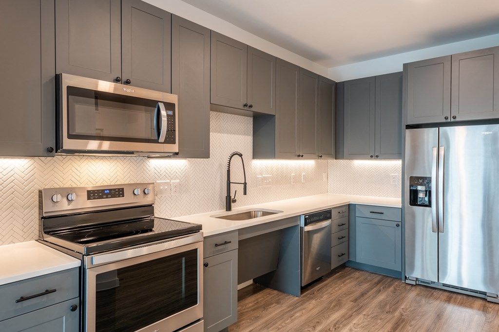 a kitchen with gray cabinets and white countertops