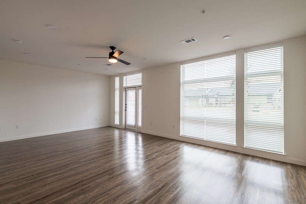 an empty living room with hardwood floors and a ceiling fan