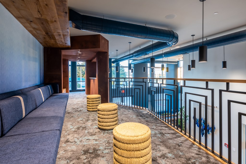 a room with a couch and stools in front of a railing