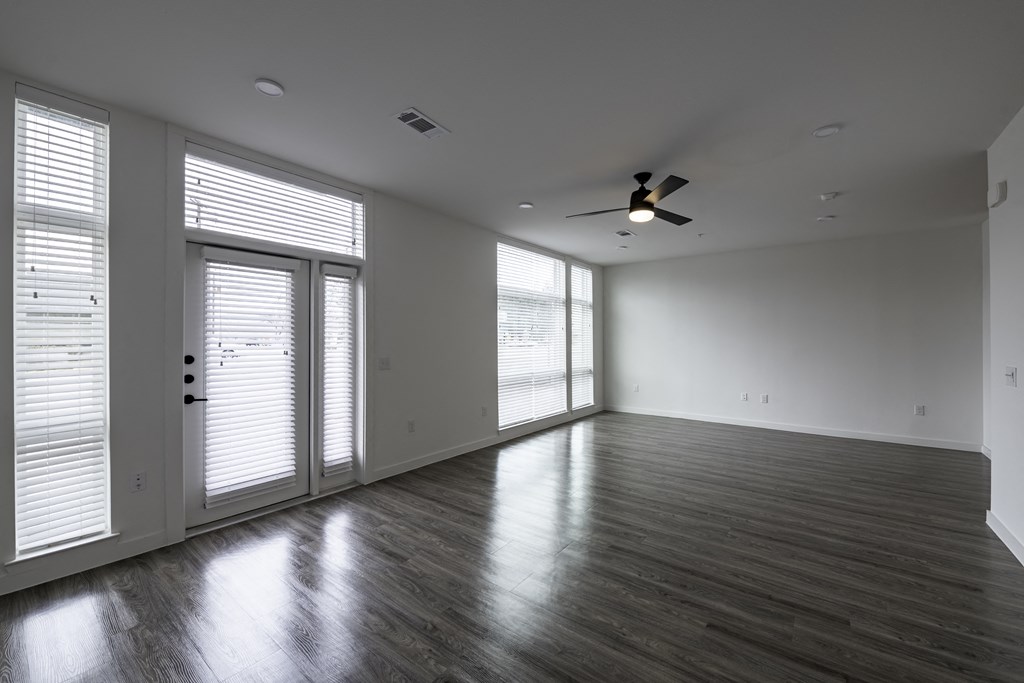 an empty living room with a ceiling fan