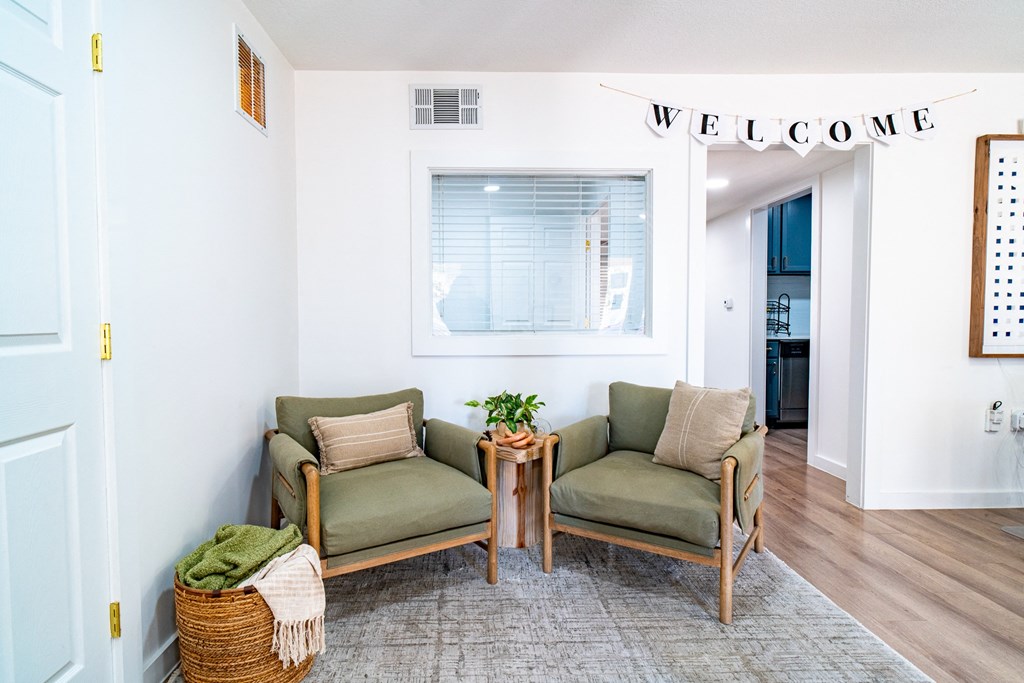 a living room with two chairs and a welcome sign on the wall