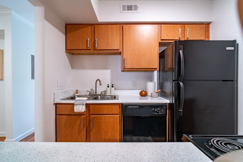 an empty kitchen with black appliances and wooden cabinets