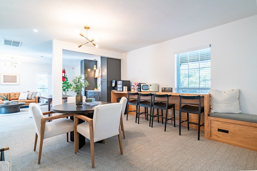 a living room with a dining room table and chairs and a kitchen with a counter