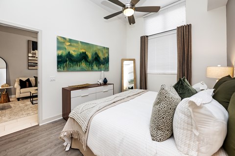 A bedroom with a large bed and a painting on the wall.