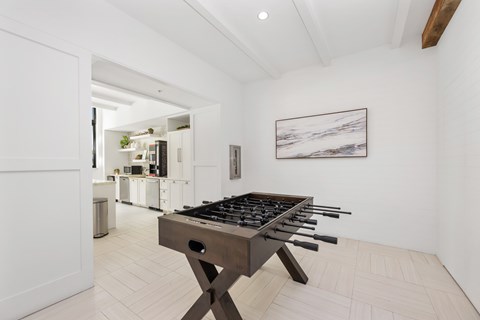 A modern kitchen with a wooden table and a painting on the wall.