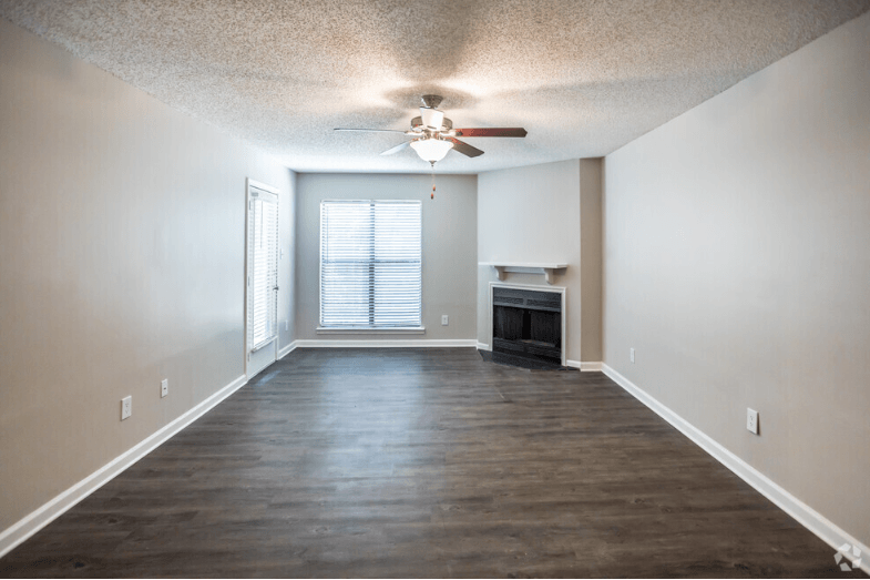 an empty living room with a fireplace and a ceiling fan