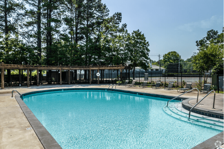 a large swimming pool with chaise lounge chairs and trees in the background