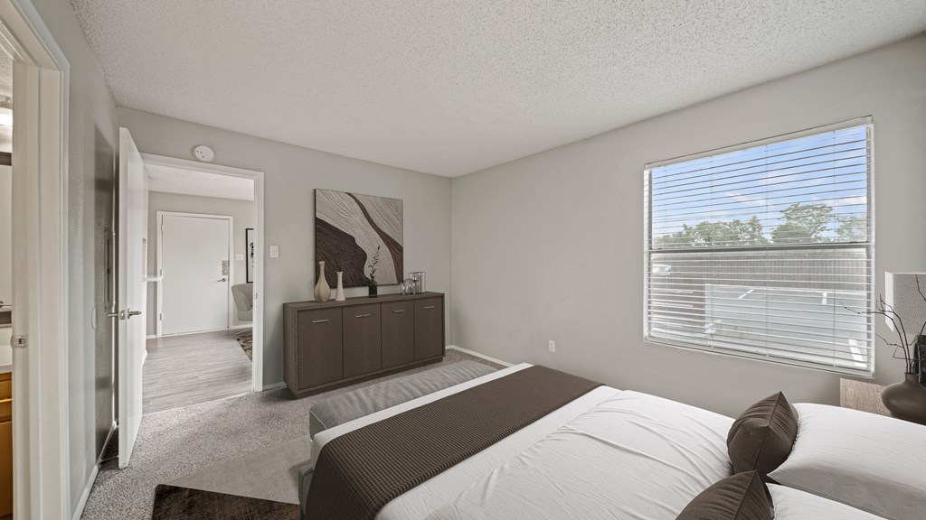 a bedroom with a bed and a large window and a door to a bathroom