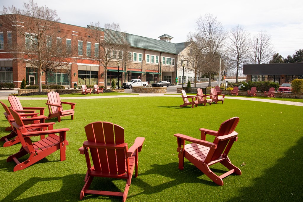 a group of red chairs on a lawn in front of a building