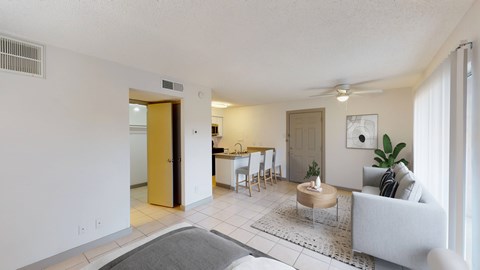 A living room with a grey couch, a round table, and a dining table with chairs.