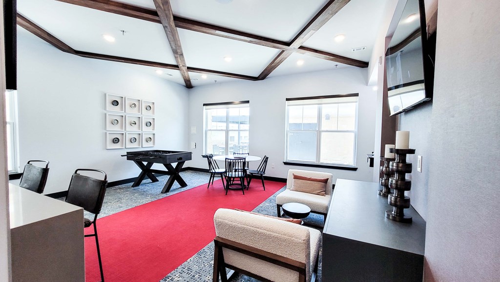 a living room with a red rug and a table with chairs