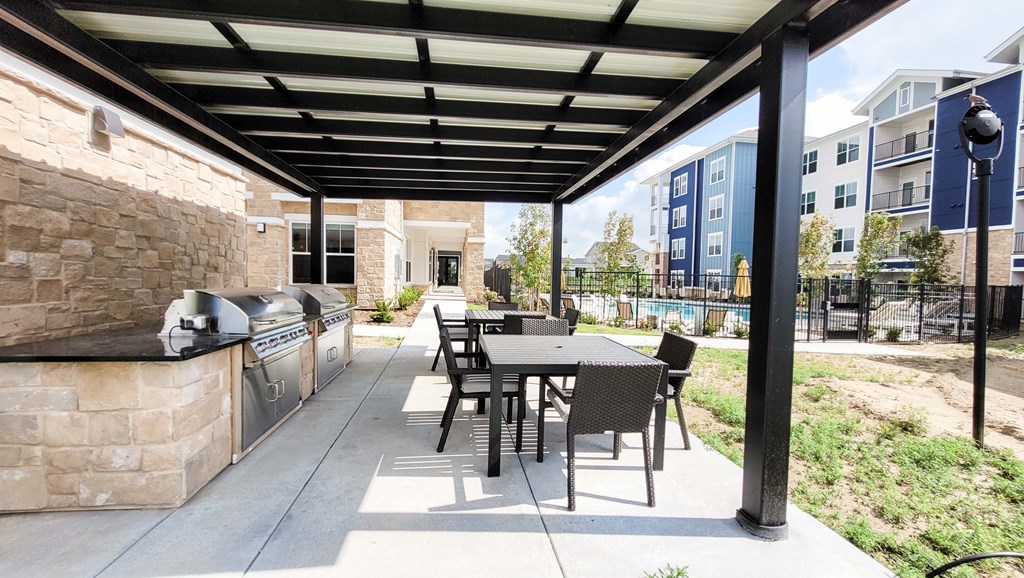 a patio with a table and chairs and a grill