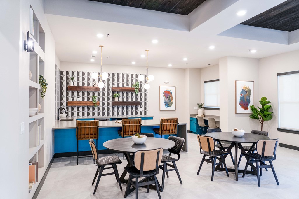 a dining room with tables and chairs and a kitchen with a blue and white wall