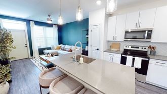 a kitchen and living room with white cabinets and a blue accent wall