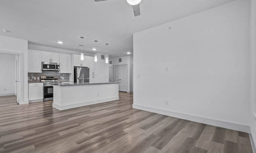 an empty living room and kitchen with white walls and wood floors