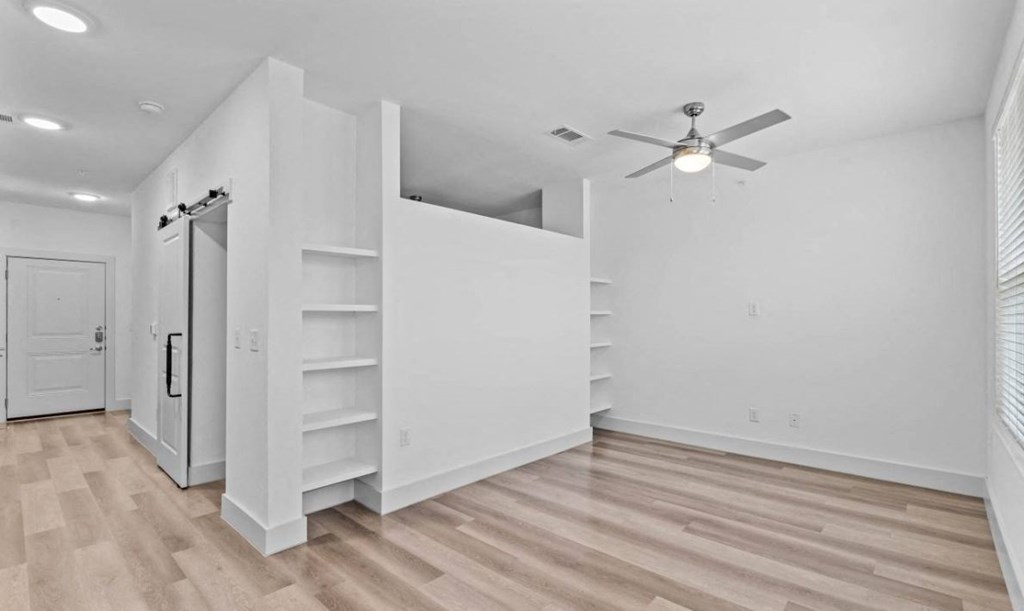 an empty living room with white walls and a ceiling fan