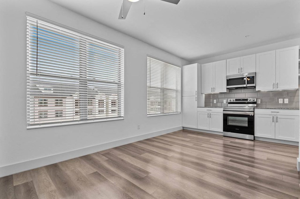 an empty kitchen with white cabinets and a large window