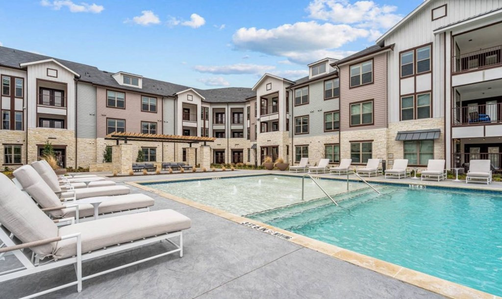 an apartment building with a swimming pool and lounge chairs