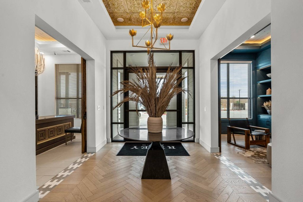 a lobby with a large plant in a vase and a glass door