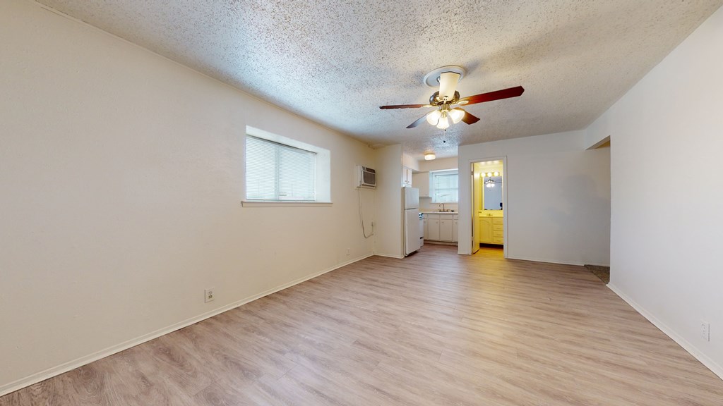 A room with a ceiling fan and wooden flooring.