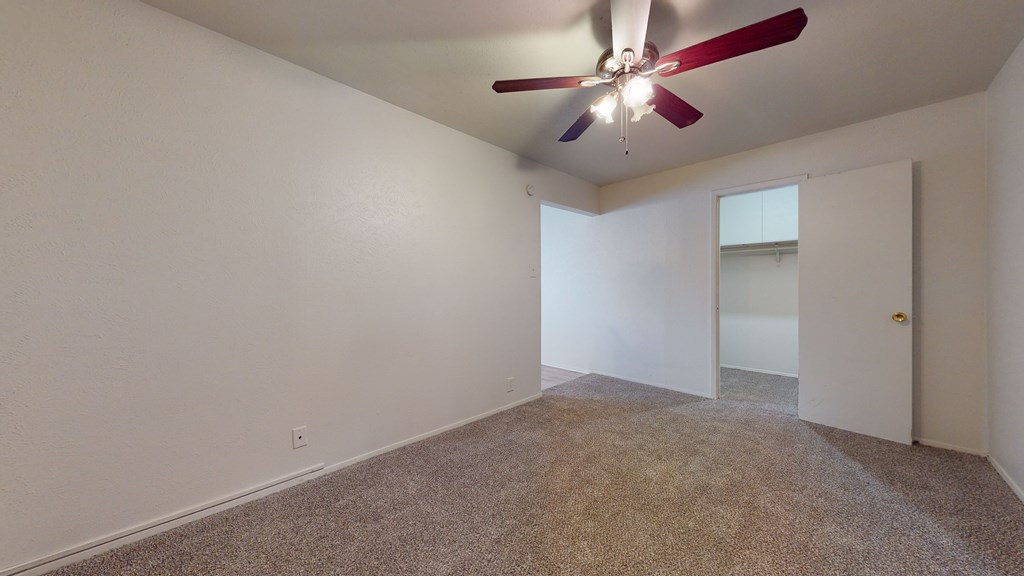 A room with a ceiling fan and carpeted floor.