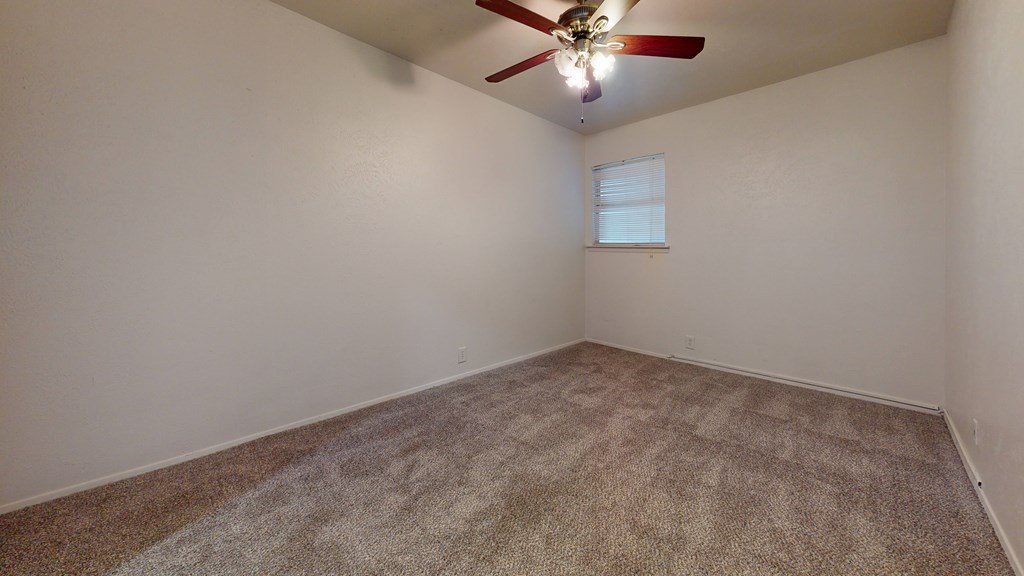 A room with a ceiling fan and carpeted floor.