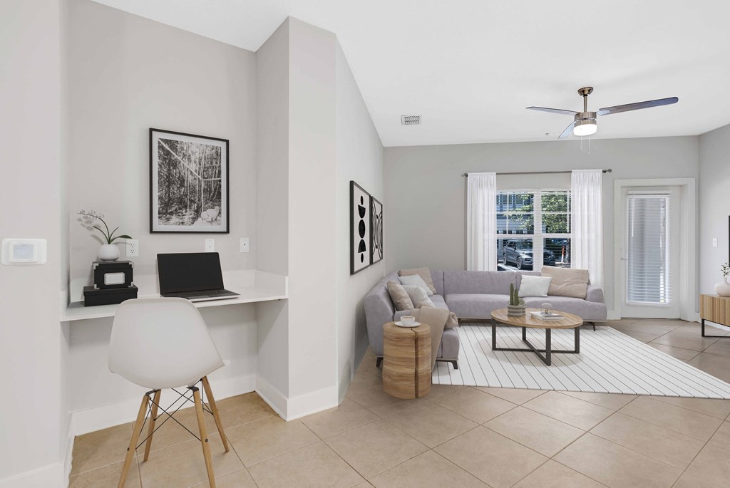 a living room with a couch and a desk with a laptop
