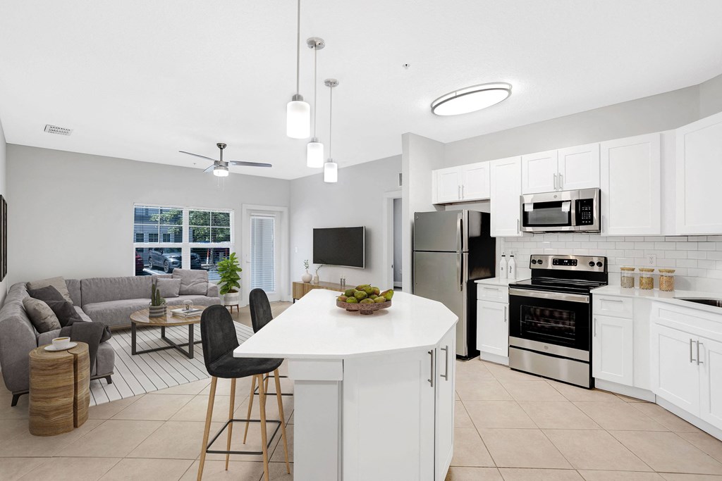 an open kitchen and living room with white cabinets and a white counter top