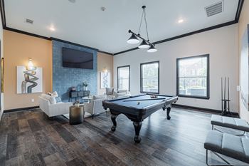 A pool table is in the middle of a room with a couch and a TV.