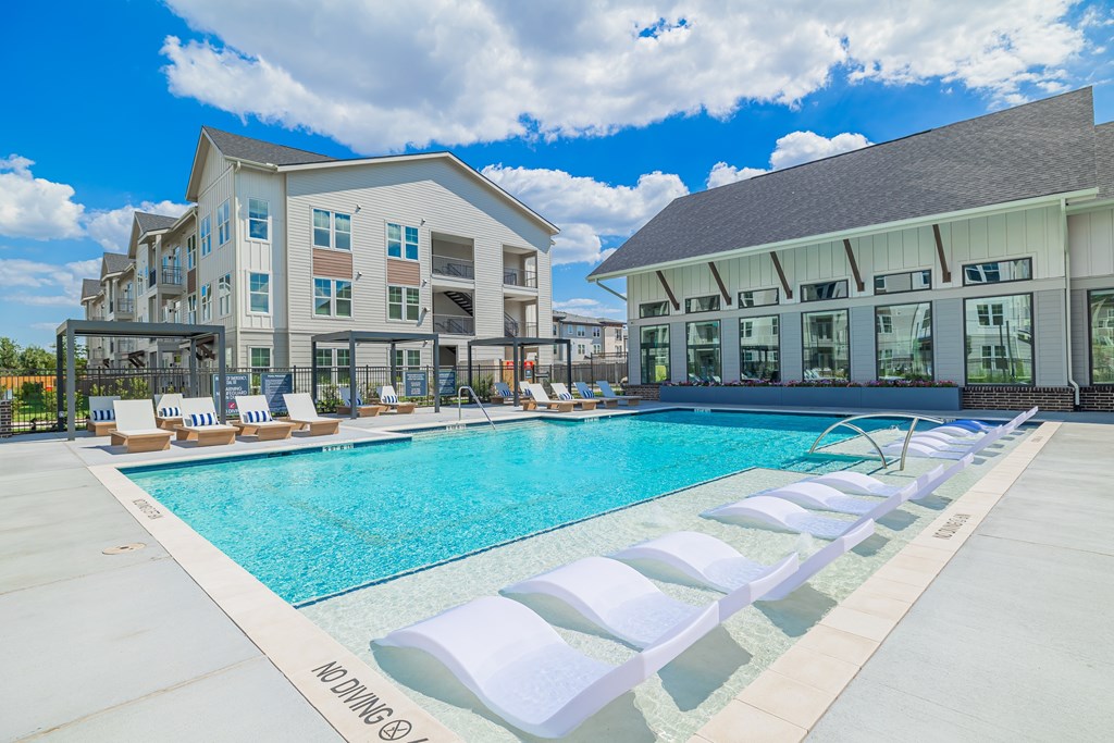 A pool with lounge chairs and a building in the background.