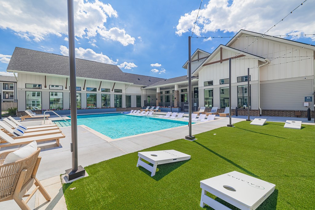 A sunny day at the poolside with lounge chairs and a building in the background.