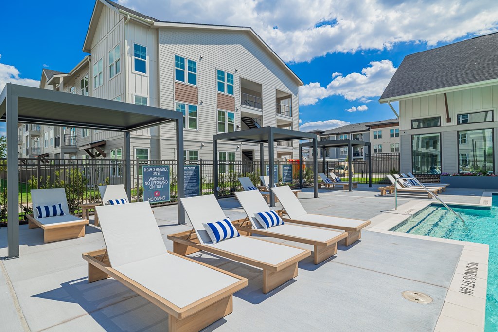 A poolside area with sun loungers and a building in the background.