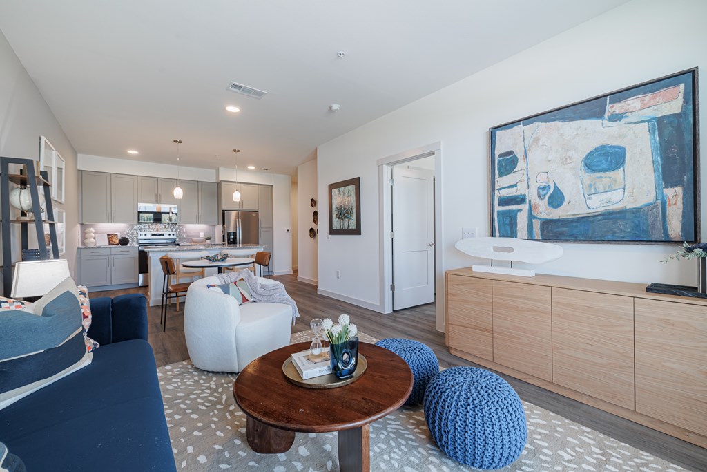 A living room with a blue couch and a painting on the wall.