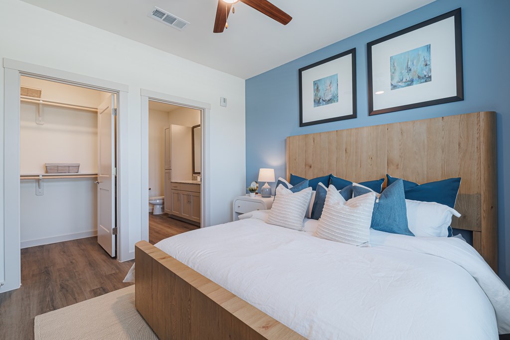 A bedroom with a large bed and two pictures on the wall.