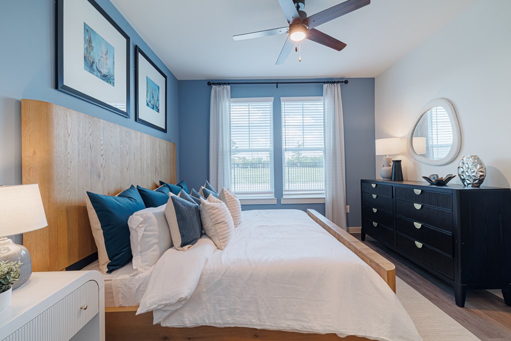 A bedroom with a bed, dresser, and ceiling fan.