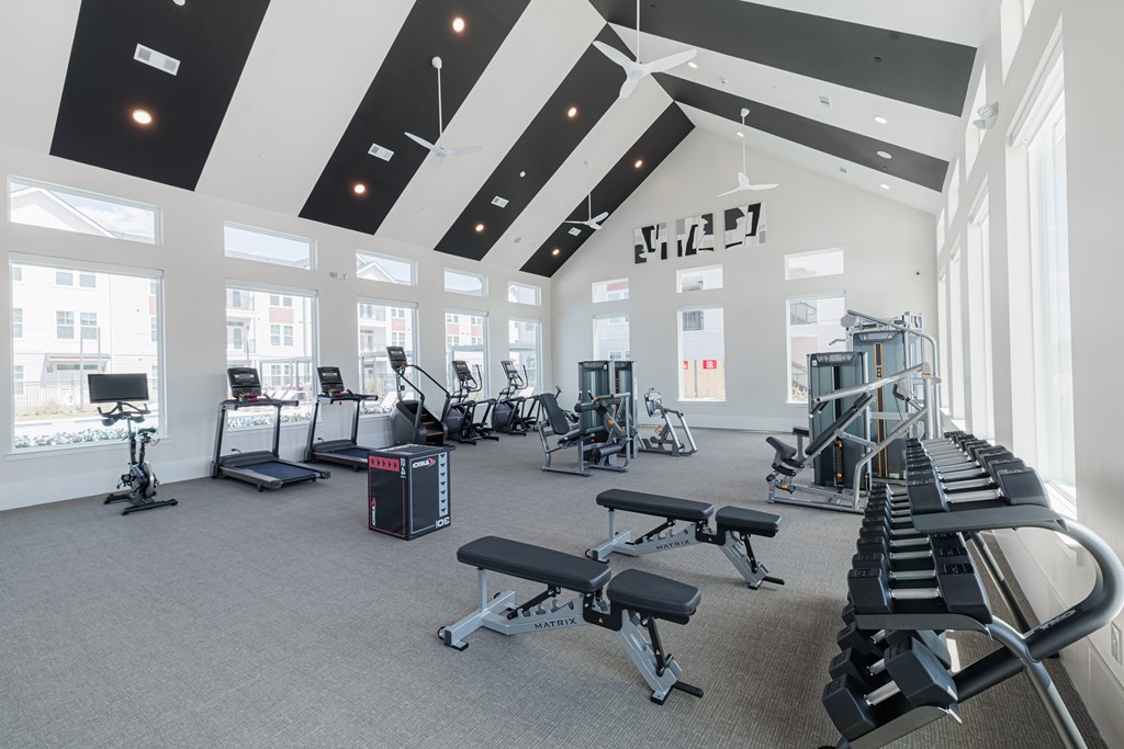 A gym with a variety of equipment including treadmills, weights, and exercise machines.