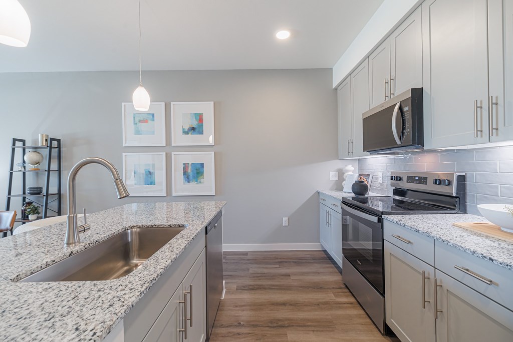 A kitchen with a sink, stove, and cabinets.
