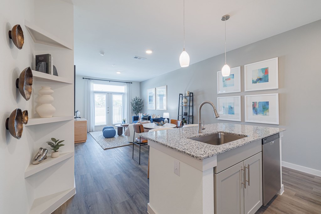 A modern kitchen with a large island and a view of the living room.