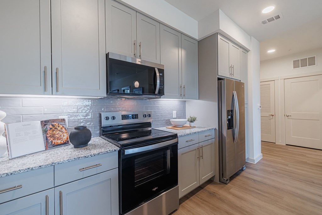 A modern kitchen with a stainless steel refrigerator and oven.