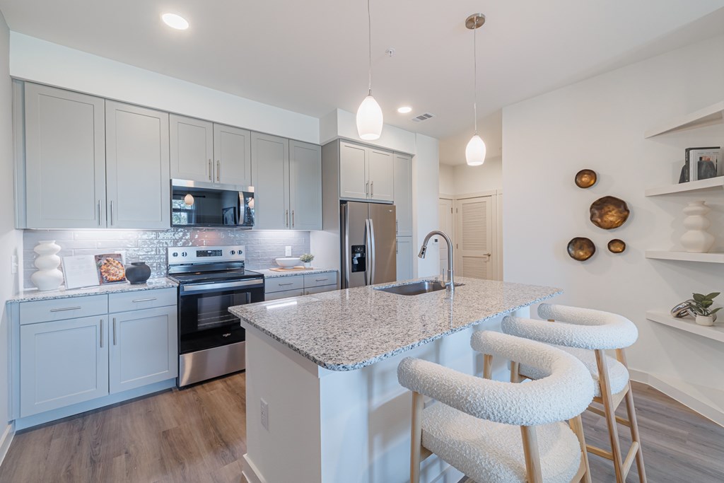 A kitchen with a granite countertop and white bar stools.
