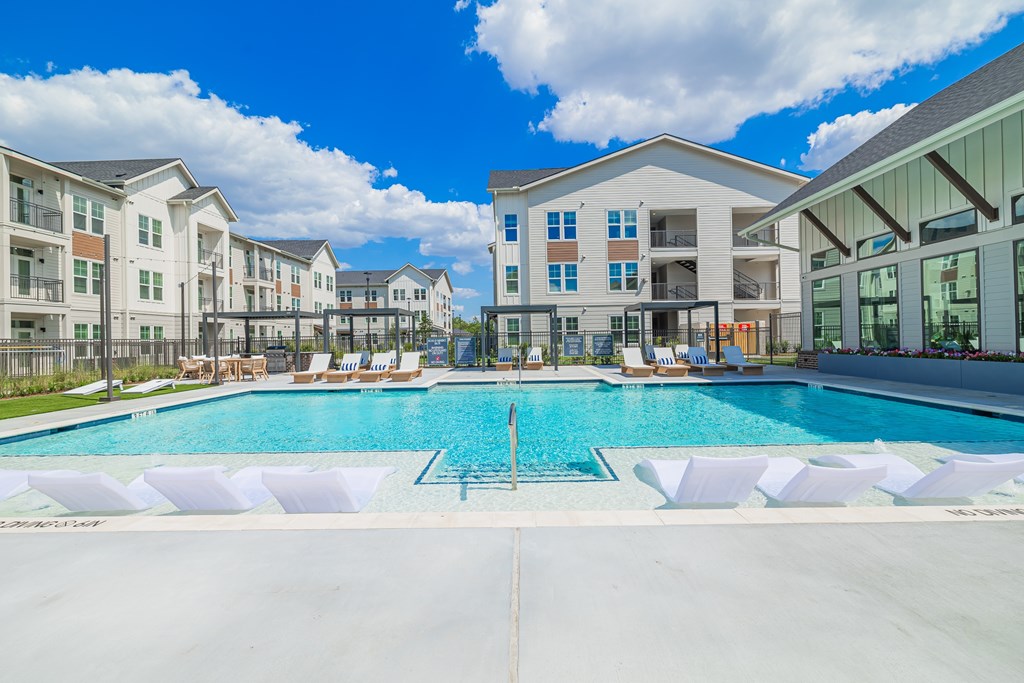 A large swimming pool in front of apartment buildings.
