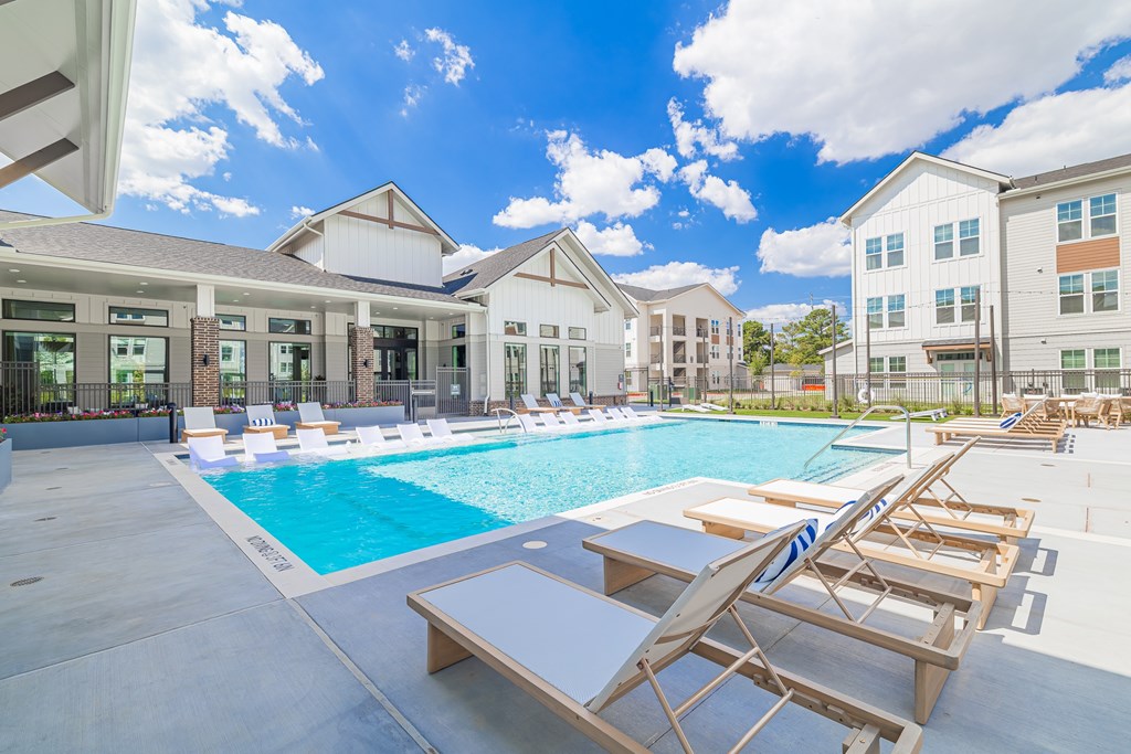 A pool with sun loungers and a building in the background.