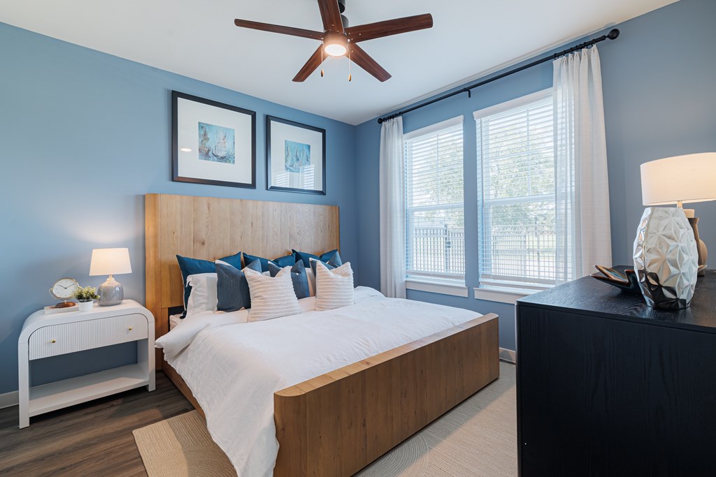 A bedroom with a bed, nightstand, and a ceiling fan.